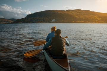Happy couple with dog  in canoe at sunset.