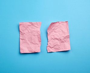 crumpled pink sheet of paper torn in two on a blue background