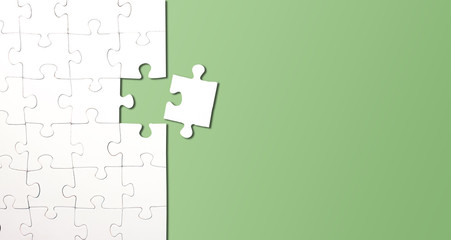 top view of jigsaw puzzle with one piece left on green background, completing a task or solving a problem concept
