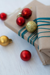 Three gifts wrapped in craft paper with bright red and gold Christmas balls in the form of balls. 