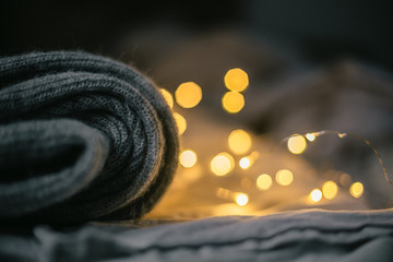 gray folded sweater on gray background and bokeh lights