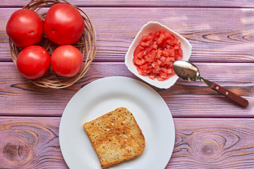 Toasted toasts and chopped tomatoes. Vegetarian bruschetta cooking with fresh tomatoes and pepper on white bread.