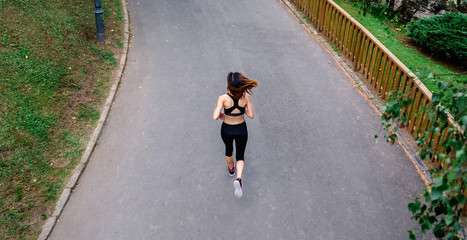 Aerial view of female athlete backwards running on a road
