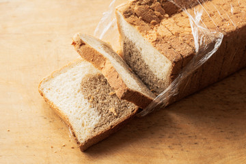 sliced bread with a separated slice lies on the cutting wooden board