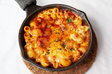 Baked macaroni and cheese with fresh tomato sauce served on hot pan