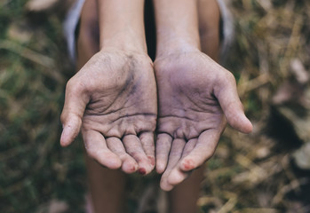 hands poor child or beggar begging you for help sitting at dirty slum. concept for poverty or hunger people,human rights,donate and charity for underprivileged children in third world 