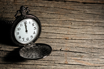 luxury vintage black pocket watch on wooden table, abstract for time concept with copy space, sepia...
