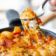 Baked macaroni and cheese with fresh tomato sauce served on hot pan