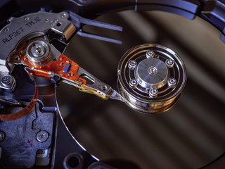 The old IDE hard disk internal components with a beautiful shiny magnetic disk.