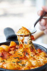 Baked macaroni and cheese with fresh tomato sauce served on hot pan
