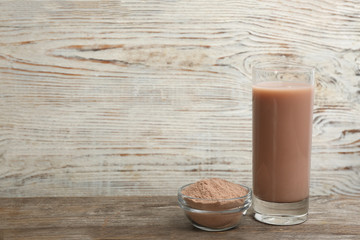 Protein shake and powder on wooden table, space for text