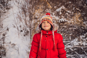 Fototapeta na wymiar Boy in red fashion clothes playing outdoors. Active leisure with children in winter on cold days. Boy having fun with first snow. Happy little kid is playing in snow, good winter weather