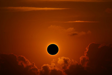 phenomenon of partial sun eclipse over silhouette orange cloud and sunset sky