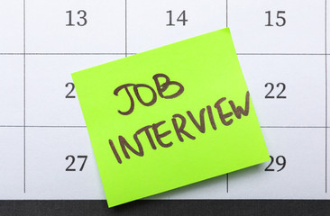 Reminder note about job interview on calendar, top view