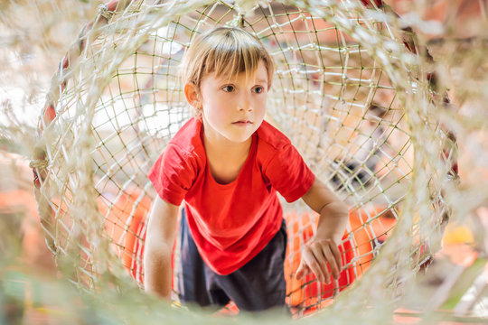 Boy crawls on a net in an obstacle course