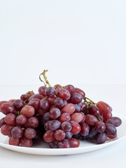 Bunch of grapes on white plate.