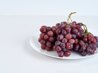 Bunch of grapes on white plate.