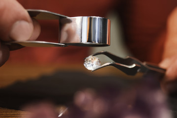 Fototapeta na wymiar Professional jeweler evaluating beautiful gemstone, closeup view