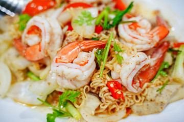 Spicy Seafood Instant Noodle Salad. Instant noodle spicy salad with shrimp, squid, Mussels, crab sticks, fresh vegetables, tomatoes, onions. Thai food style.