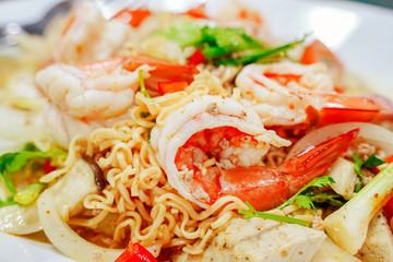 Spicy Seafood Instant Noodle Salad. Instant noodle spicy salad with shrimp, squid, Mussels, crab sticks, fresh vegetables, tomatoes, onions. Thai food style.