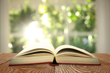 Open old hardcover book on wooden table indoors