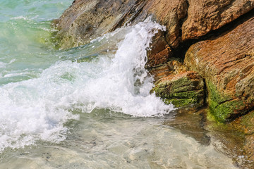 Splash of sea water waves hitting the rocky beach