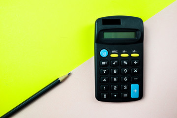 Pencil and calculator on yellow and pink  background.