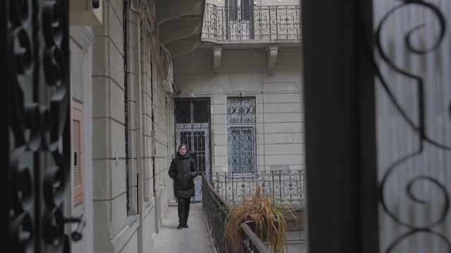 Girl walks on the balcony of old apartment house vintage style retro terrace autumn young woman in a black down jacket