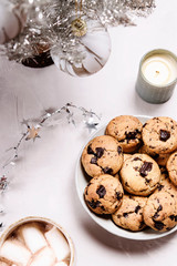 Homemade whisky and chocolate rye cookies,  silver artificial Christmas tree, tinsel and perfumed candle on grey background. Christmas cookies. Selective focus