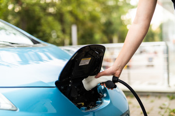 Man charging electric car. Man holding in hand power cable supply ready to plugged in into charging port.