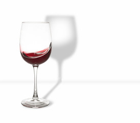 A glass of red wine and waves with a shadow on a white background. Free space for text