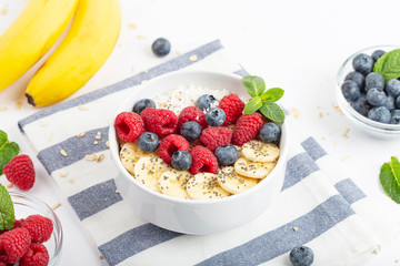 Breakfast smoothie with granola, yogurt, fresh raspberries, blueberries, bananas, coconut flakes, Chia seeds and mint. Healthy food. Breakfast food.