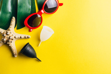 Blue Menstrual cup with a blue deck chair on a peach pastel background. The concept of simplicity and comfort of using the menstrual cup in travel.