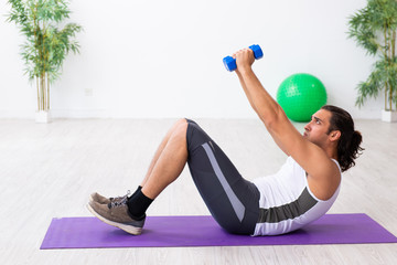 Young handsome man doing sport exercises indoors