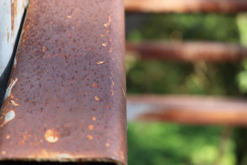 The iron railing is damaged, has rust, the back is blurred.