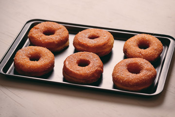 Fried Donuts with Powdered Sugar on metal baking dish