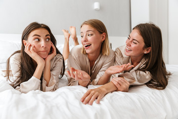 Three cheerful girls friends wearing dressing gowns - obrazy, fototapety, plakaty