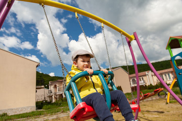 Little boy riding on a swingin and having fun in park
