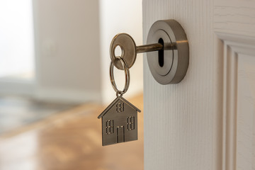 Open door to a new home with key and home shaped keychain. Mortgage, investment, real estate,...