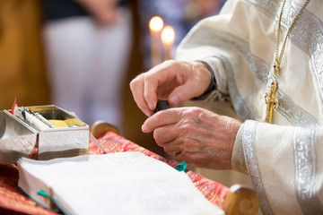 Obraz premium Orthodox religion. Hands of the priest against the background of the cross and candles.
