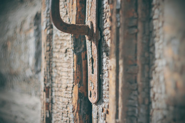 An old wooden door, its paint crumbling with age and its metal handle rusted through, lit by light.