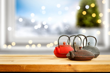 Naklejka na ściany i meble Kettle brower on wooden table and free space for your product. Blurred window sill background with chrsitmas tree and lights.Landscape of mountains and winter time.Copy space and sun light. 