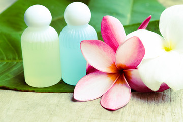 Soft focus, spa equipment and beautiful plumeria flowers resting on natural green leaves.