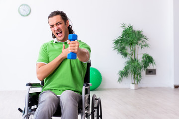 Young man in wheel-chair doing exercises indoors