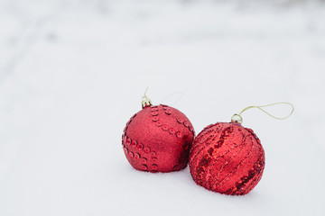 Two large red Christmas balls with decoration on white snow