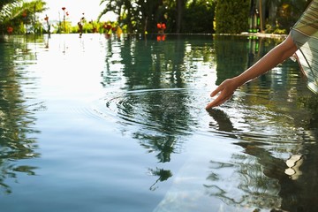 Woman Touching Water Of Swimming Pool