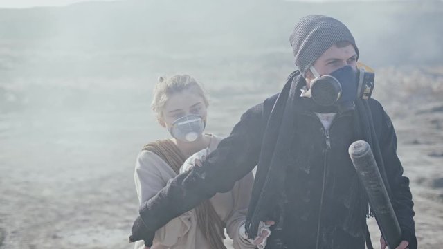 Couple of survivors in post apocalyptic wasteland are defending from the enemy with baseball bat.