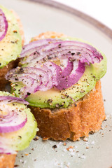 Sandwich with fresh avocado and onion on a plate