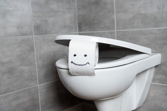 Toilet paper with smile sign on toilet bowl in restroom