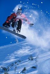 Snowboarder In Midair With Snow Powder Trailing Behind